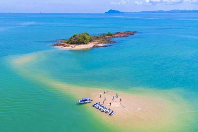 Aerial view of a small sandbar island with jet skis lined up and guests taking a beach break in Phuket.